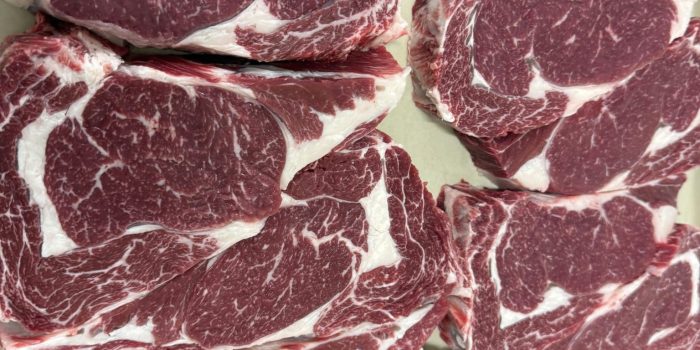 A tray of freshly cut Rafter 39 Cattle Co. Wagyu ribeye steaks showing rich, intricate white marbling throughout the deep red beef.